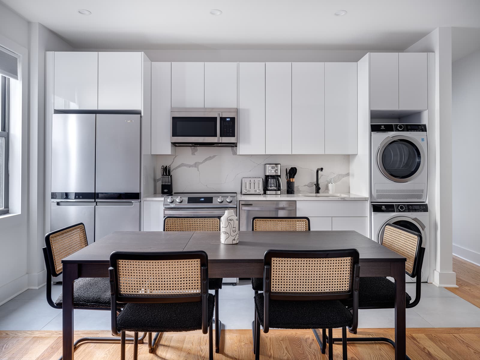 Full kitchen with marble backsplash, stainless fridge, range and stacked washer and dryer
