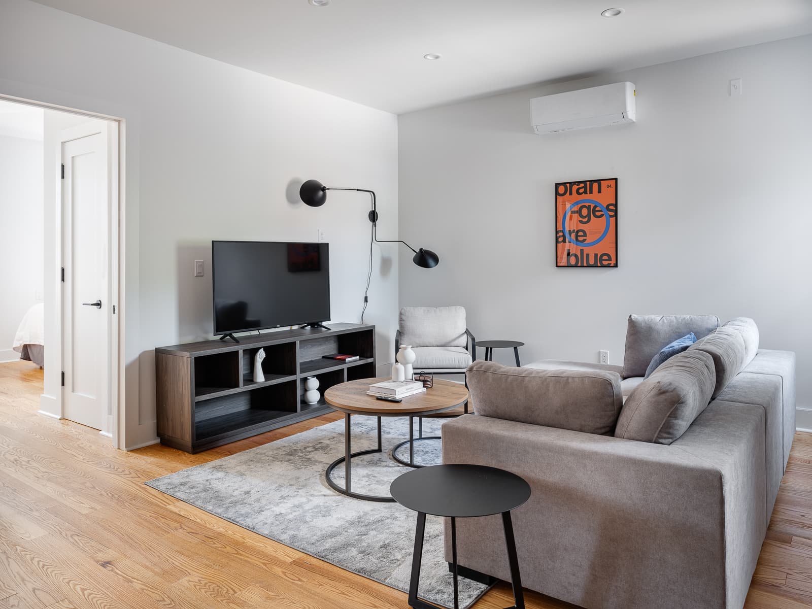 Bright living room with sectional sofa, black swing-arm wall lamp and oak floors
